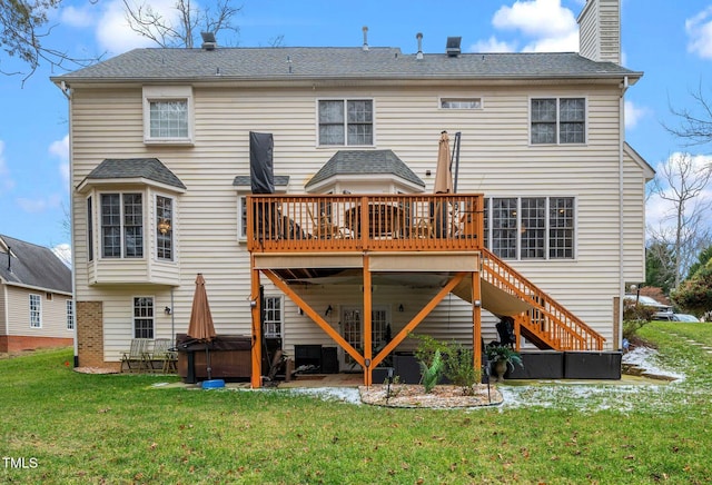 rear view of property with a hot tub, a yard, and a deck