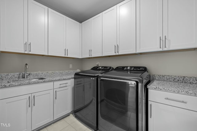 clothes washing area with sink, light tile patterned floors, cabinets, and washer and dryer