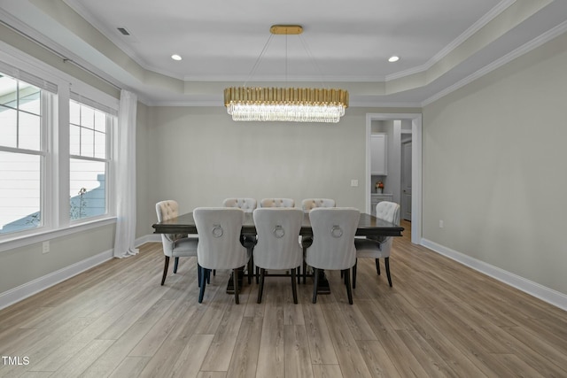 dining area featuring crown molding, light hardwood / wood-style flooring, and a raised ceiling