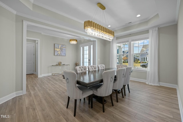 dining room featuring french doors, crown molding, a tray ceiling, and light hardwood / wood-style flooring