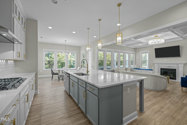 kitchen with sink, white cabinetry, pendant lighting, stainless steel appliances, and a kitchen island with sink