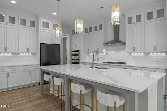 kitchen with white cabinetry, stainless steel appliances, sink, and an island with sink