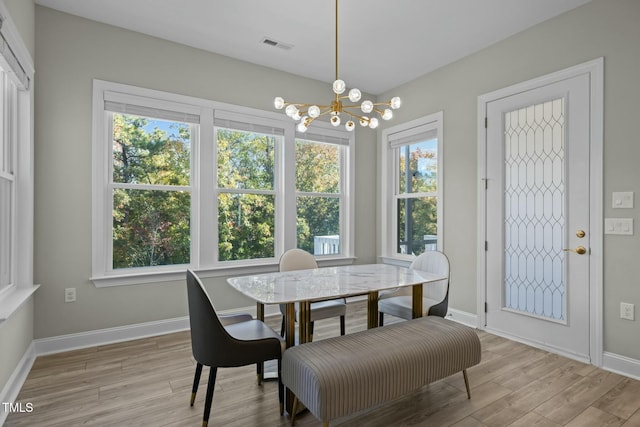 dining room featuring a notable chandelier, a wealth of natural light, and light wood-type flooring