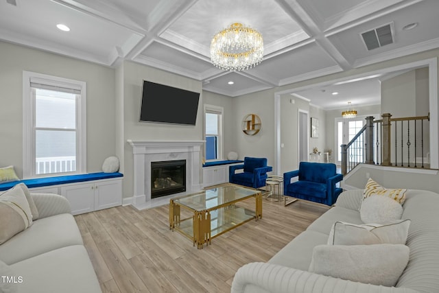 living room with coffered ceiling, a fireplace, light hardwood / wood-style flooring, and a notable chandelier