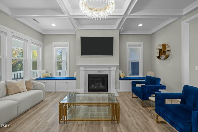 living room with coffered ceiling, an inviting chandelier, a high end fireplace, and light hardwood / wood-style floors