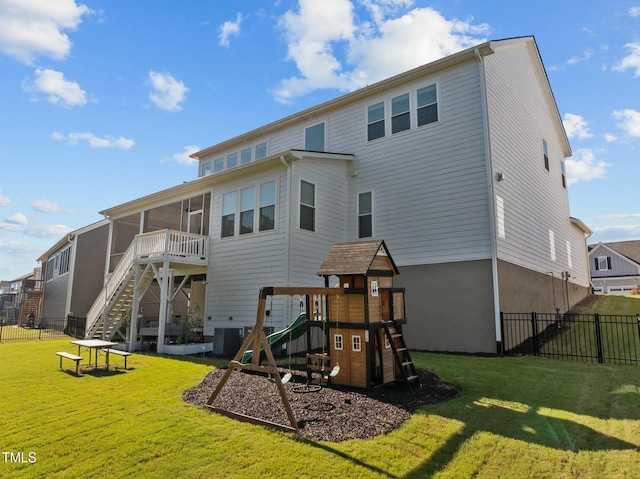 back of house with central AC unit, a playground, and a lawn