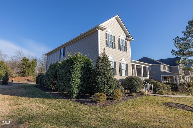 view of side of home featuring a sunroom and a lawn