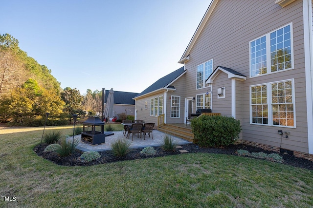 back of property featuring a wooden deck, a yard, and a patio