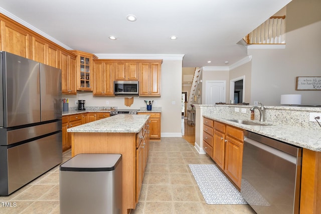 kitchen with sink, light stone counters, ornamental molding, a kitchen island, and stainless steel appliances