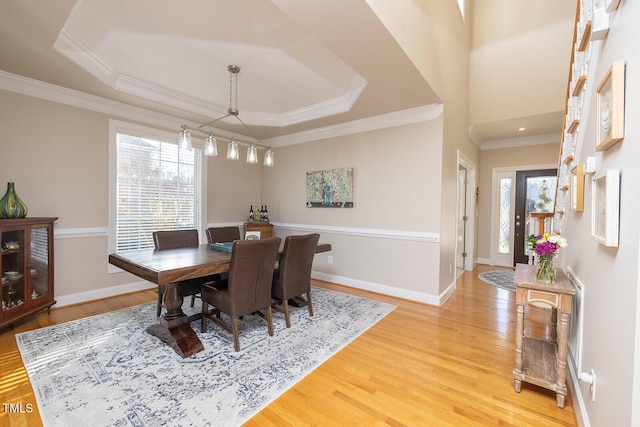 dining area with a wealth of natural light, ornamental molding, hardwood / wood-style floors, and a tray ceiling