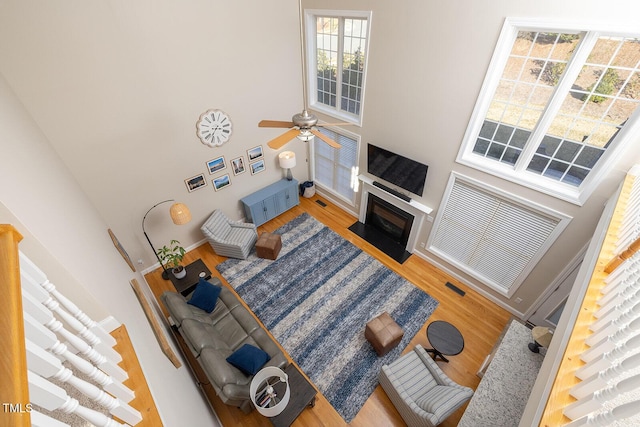 living room with hardwood / wood-style flooring, ceiling fan, and a high ceiling