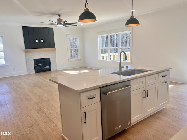 kitchen with sink, stainless steel dishwasher, white cabinetry, and decorative light fixtures