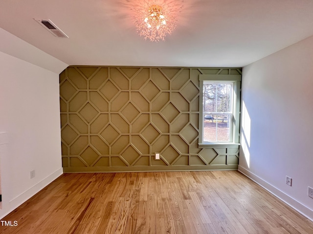 empty room with light hardwood / wood-style floors and an inviting chandelier