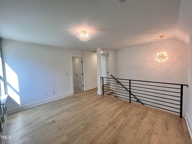 empty room featuring light wood-type flooring and a chandelier