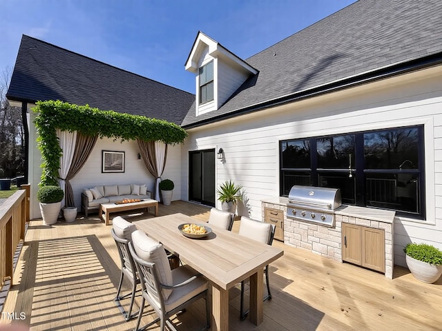 wooden terrace with outdoor lounge area, area for grilling, and exterior kitchen