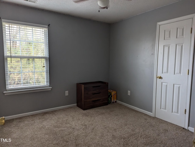 carpeted spare room featuring ceiling fan, plenty of natural light, and a textured ceiling