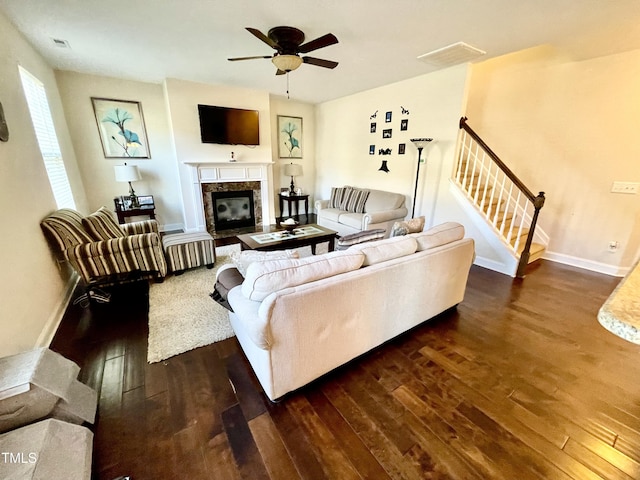 living room featuring ceiling fan, dark hardwood / wood-style floors, and a fireplace