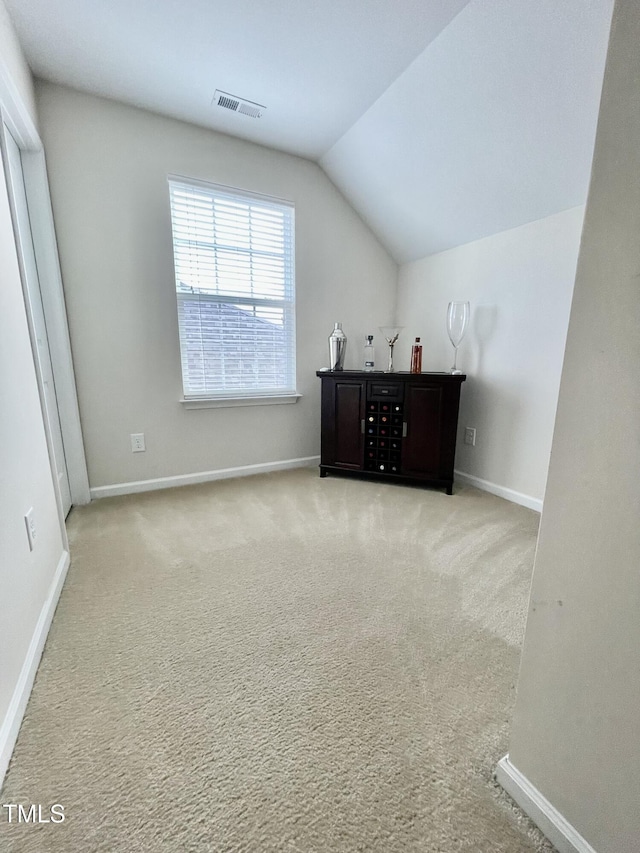 bonus room with lofted ceiling and light carpet