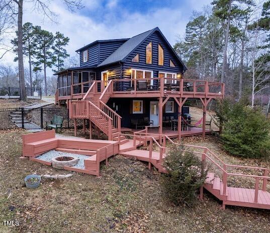 back of house with a fire pit, a sunroom, and a deck