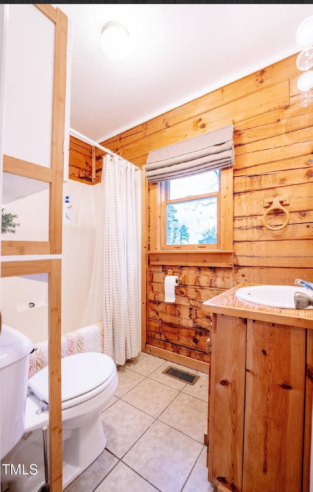 bathroom featuring tile patterned flooring, vanity, wooden walls, and toilet