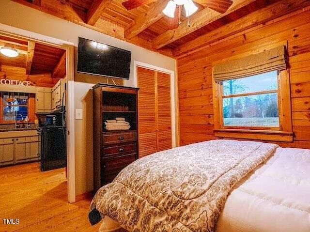 bedroom with beamed ceiling, wood walls, light hardwood / wood-style floors, and wooden ceiling