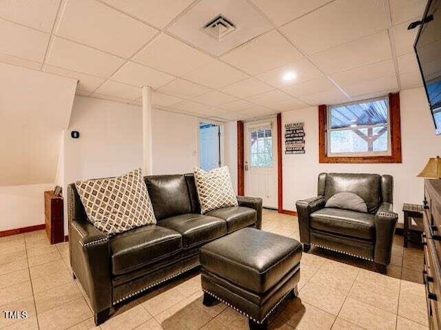 living room with light tile patterned floors and a paneled ceiling