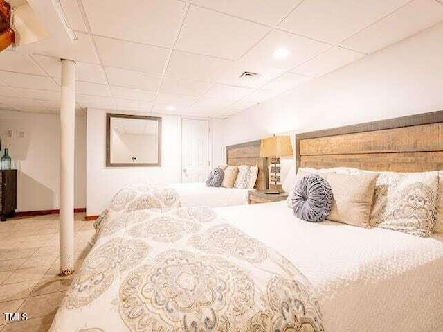 bedroom featuring a paneled ceiling and tile patterned floors