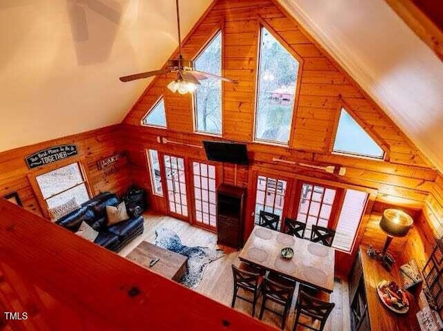 living room featuring a healthy amount of sunlight, high vaulted ceiling, and wood walls