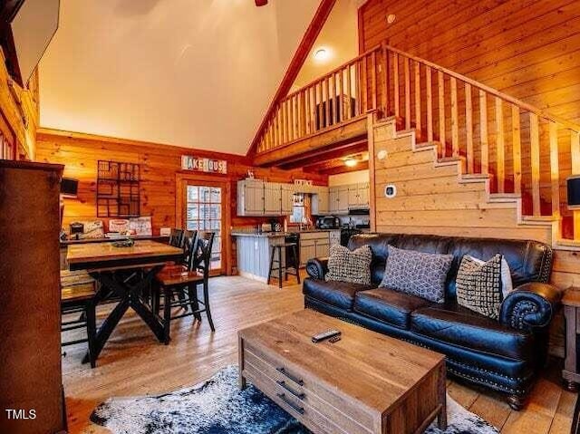 living room featuring light hardwood / wood-style floors, a high ceiling, and wood walls