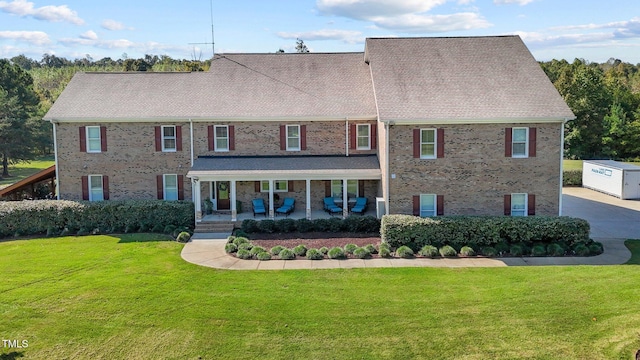 colonial house with a front yard and a patio