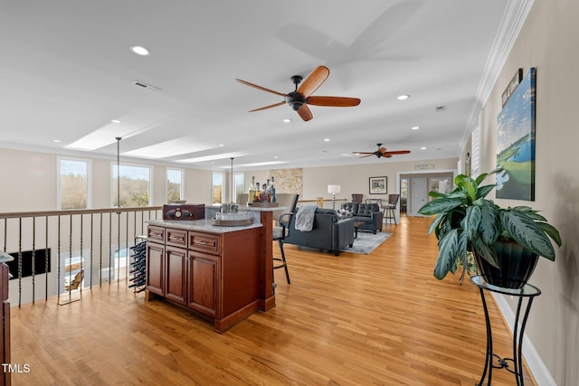 kitchen with decorative light fixtures, a kitchen breakfast bar, a center island, and light wood-type flooring