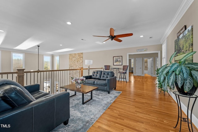 living room with ceiling fan, ornamental molding, and light wood-type flooring