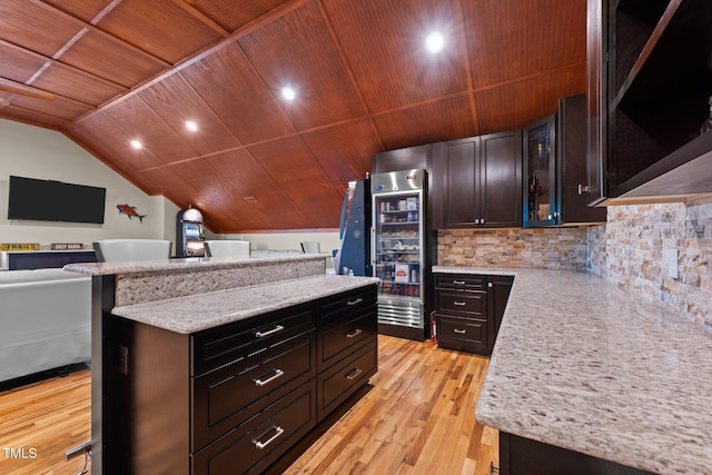 kitchen with vaulted ceiling, light hardwood / wood-style floors, a breakfast bar area, and wooden ceiling