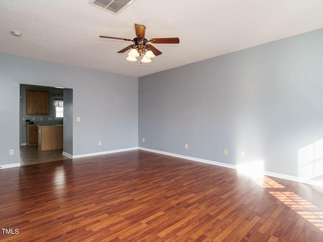 empty room featuring ceiling fan, dark hardwood / wood-style flooring, and a textured ceiling