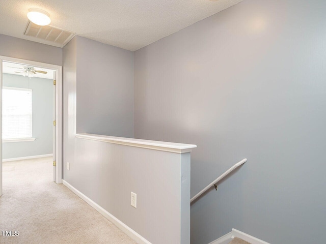 hallway featuring light carpet and a textured ceiling