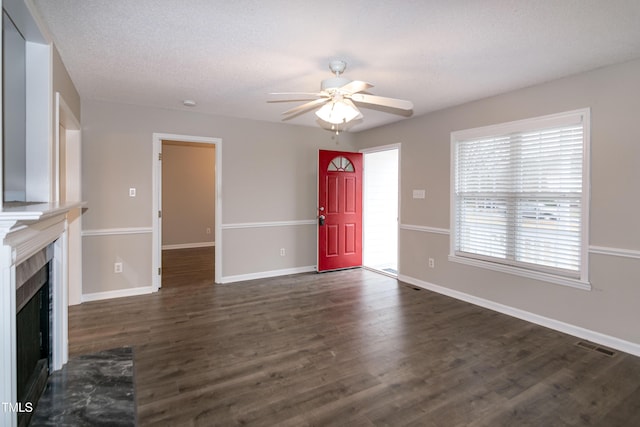 unfurnished living room with ceiling fan, a textured ceiling, and dark hardwood / wood-style flooring