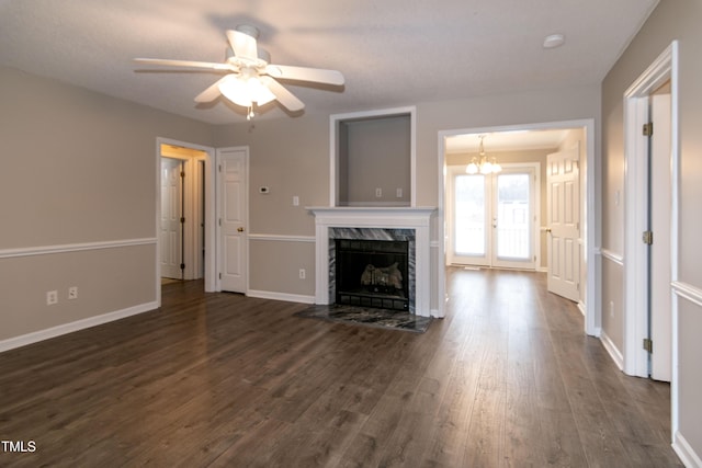 unfurnished living room with a fireplace, dark hardwood / wood-style floors, and ceiling fan with notable chandelier