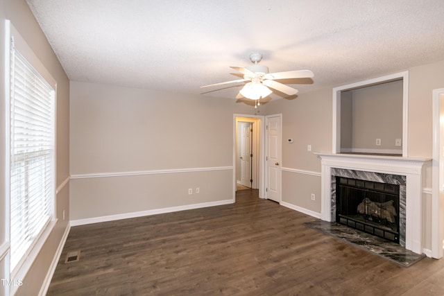 unfurnished living room featuring dark hardwood / wood-style flooring, a textured ceiling, a high end fireplace, and ceiling fan