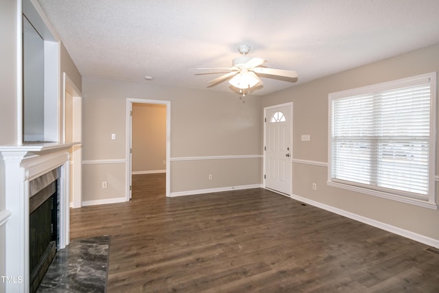 unfurnished living room featuring ceiling fan, a textured ceiling, and dark hardwood / wood-style flooring