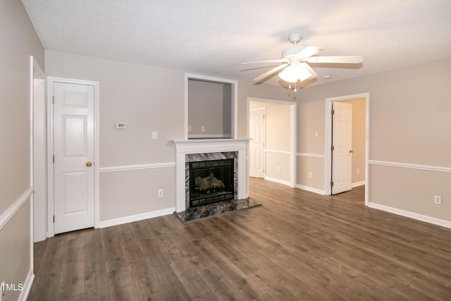 unfurnished living room featuring dark wood-type flooring, ceiling fan, a high end fireplace, and a textured ceiling