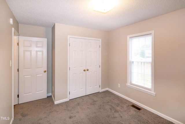 unfurnished bedroom featuring carpet, a textured ceiling, and a closet