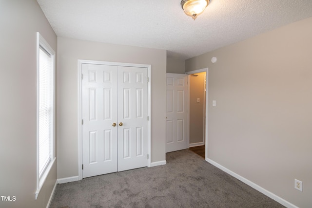 unfurnished bedroom featuring multiple windows, light colored carpet, a textured ceiling, and a closet