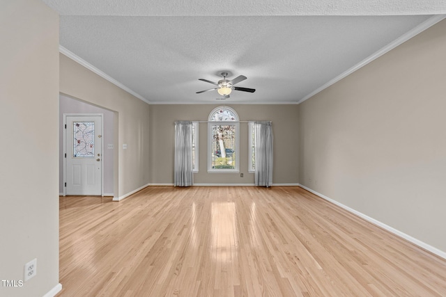 empty room with baseboards, a ceiling fan, a textured ceiling, crown molding, and light wood-type flooring