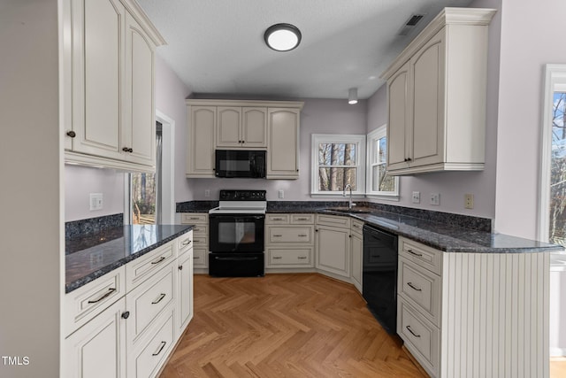 kitchen featuring a textured ceiling, a sink, visible vents, black appliances, and dark stone countertops