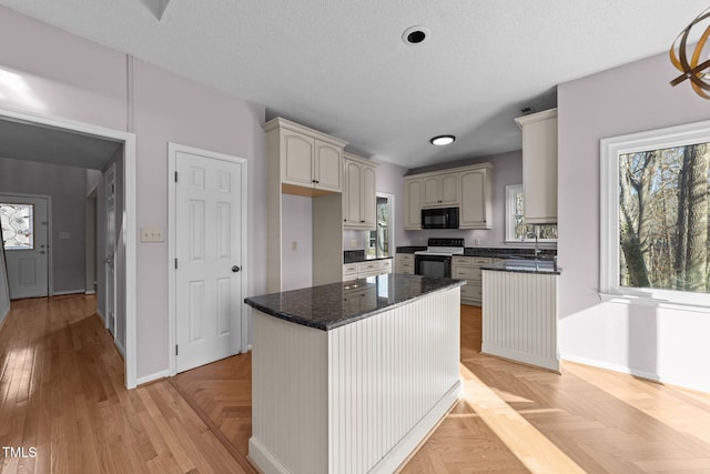 kitchen featuring electric stove, black microwave, a healthy amount of sunlight, and a textured ceiling