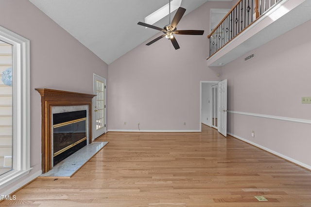 unfurnished living room featuring a fireplace, ceiling fan, high vaulted ceiling, light wood-type flooring, and baseboards