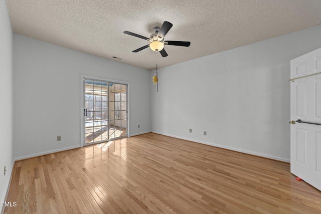 empty room with visible vents, a ceiling fan, a textured ceiling, light wood-type flooring, and baseboards