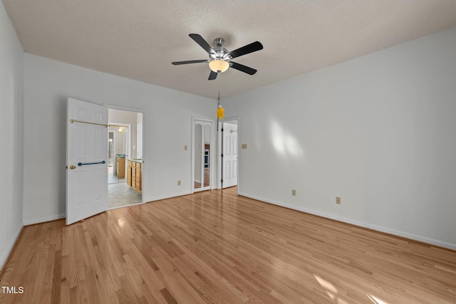 unfurnished bedroom with a textured ceiling, ceiling fan, connected bathroom, baseboards, and light wood-type flooring