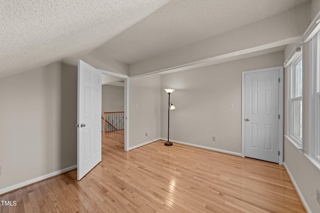 unfurnished bedroom featuring light wood finished floors, baseboards, and a textured ceiling