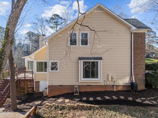 view of side of home with a deck, crawl space, a chimney, and stairs